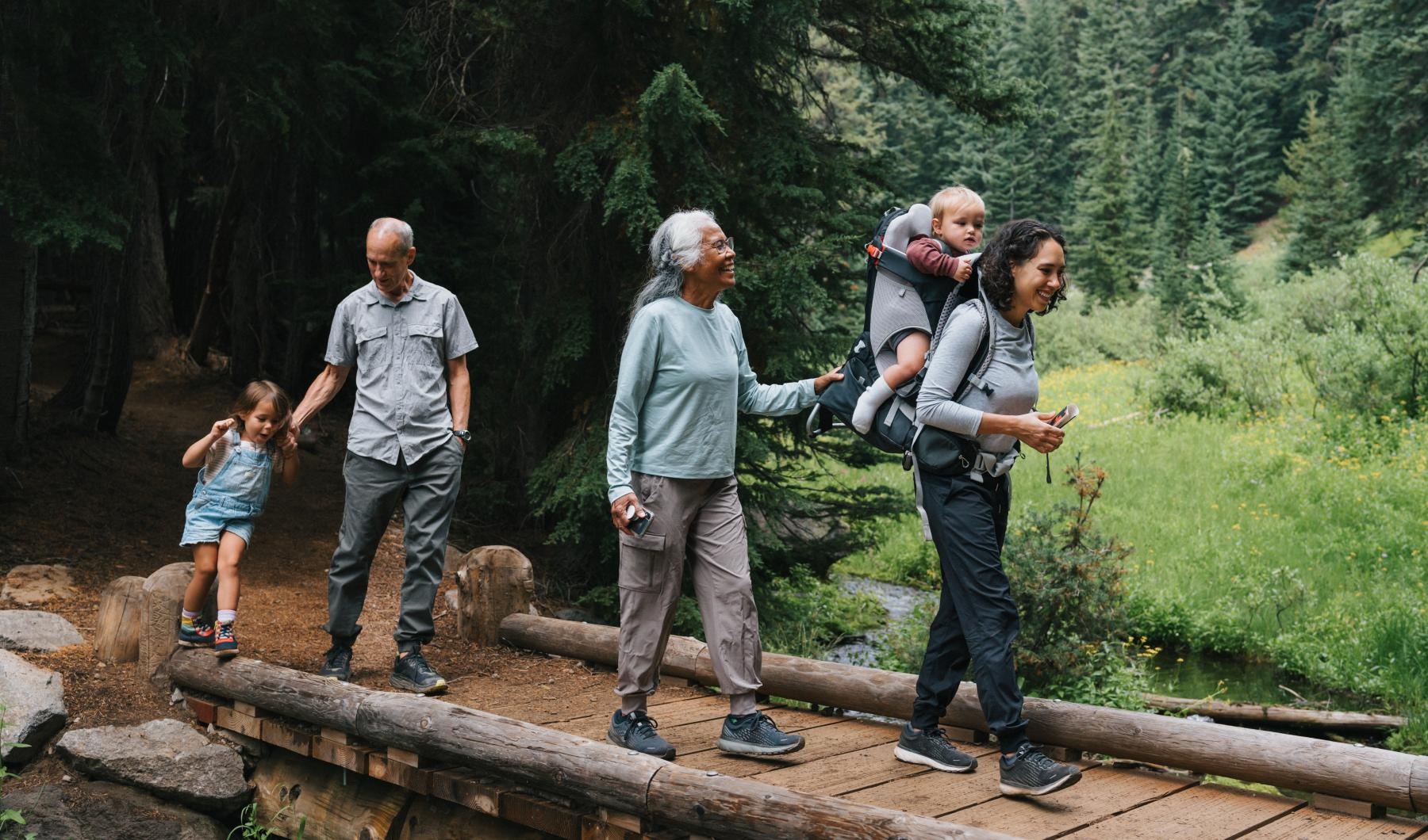 Close to the center of everything a group of people standing on a log in a forest
